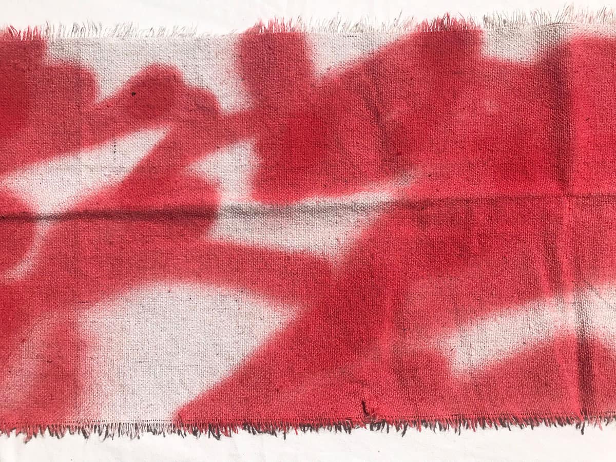 piece of canvas with red spray paint lines